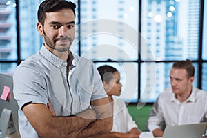 Portrait of successful young businessmanÂ at office, colleagues in background